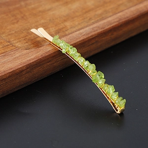 Detailed close-up of green crystal stones on a gold-plated minimalist hair clip