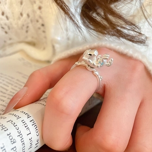 Detail of a matte silver ring with a 3D pig design and blue heart on model finger