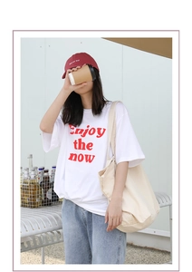 Detail view of retro beige canvas bag paired with a casual white logo graphic t-shirt