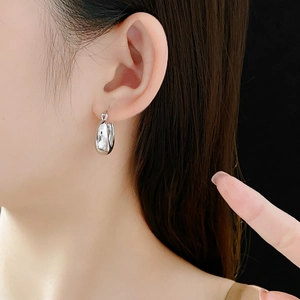 Close-up of minimalist U-shaped silver mirror hoop earrings worn by a model