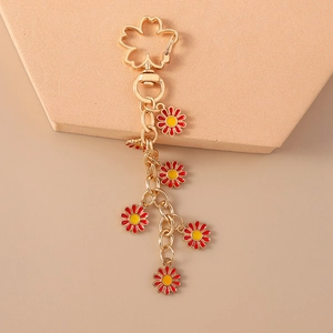 Detail showing red and yellow daisy charms on a golden metal keychain link