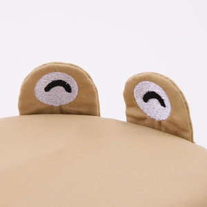 Gros plan sur la broderie œil de grenouille sur toile de coton kaki pour chapeau bébé