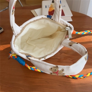 Detailed interior of quilted crossbody bag featuring bear print and colorful braided strap