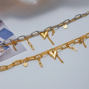 Detail of two-tone 18K gold and silver chunky chain bracelets with heart and star charms