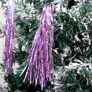 Macro detail of purple holographic laser tinsel on snow-dusted Christmas tree branches