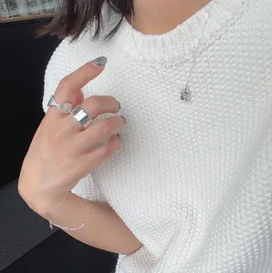 Detail of 925 sterling silver rings and pink beaded bracelet on white knit background