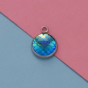 Macro detail van ronde zilveren hanger met glanzende blauwe vissen schubben hars inleg