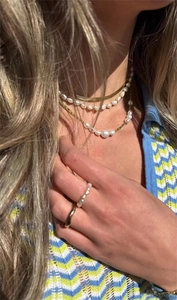 Nahaufnahme von goldener Schlangenkette, Perlen-Choker und grüner Perlenkette am Model