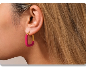 Détail d'un mannequin portant des boucles d'oreilles en émail fuchsia et or en forme de U