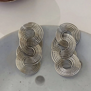 Detailed view of silver spiral hollow earrings displayed on a grey ceramic tray