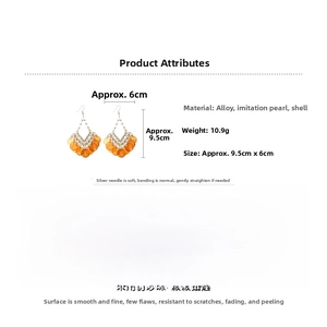 Detail view of bohemian fan-shaped drop earrings with white pearls and orange shell sequins