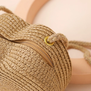 Close-up of woven straw texture with metal eyelets and zipper on a mini beach bag