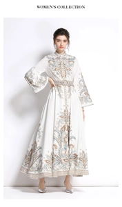 Dettaglio di un abito lungo boho bianco con motivo paisley, maniche lunghe e cintura in metallo