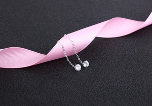 Detail of S925 silver threader earrings with zircon stones and pink ribbon styling