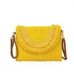 Detail of yellow raffia woven crossbody bag with layered fringe and leather strap