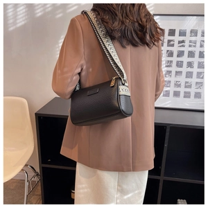 Detail einer schwarzen Tasche mit Lychee-Maserung und buntem geometrischem Gurt