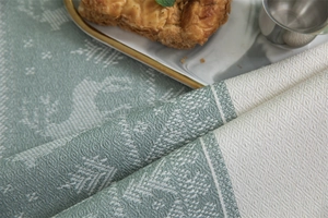 Detail of green Christmas deer jacquard tablecloth fabric with woven reindeer and tree textures