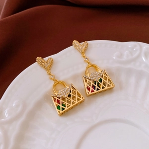 Detail of gold heart stud with crystal handbag pendant on a white ceramic plate