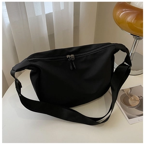 Detail of black nylon crescent bag with double zipper and adjustable strap on desk