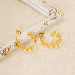 Detailed view of golden hoop earrings featuring intricate leaf pattern carvings