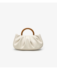 Close-up of pleated cream cloud handbag with a brown resin round handle and soft texture