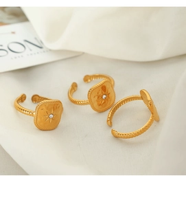 Detail of three gold plated titanium rings with star engraving and diamond on white fabric