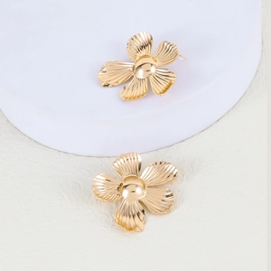 Detailed view of golden five-petal flower earrings with textured metallic finish