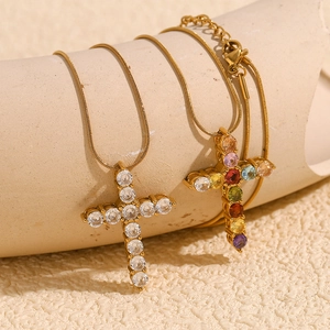 Detail of 18K gold-plated cross pendants with clear and colorful gemstones on snake chains