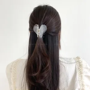 Detail of frosted heart hair claw clip holding long hair in a sleek low ponytail