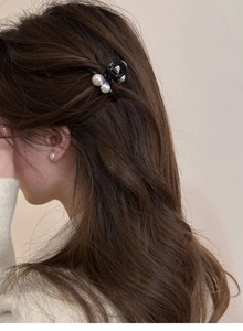 Détail de la pince à cheveux en perles noires et boucles d'oreilles sur cheveux bouclés