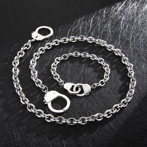Silver punk style stainless steel handcuff necklace and bracelet set on black background