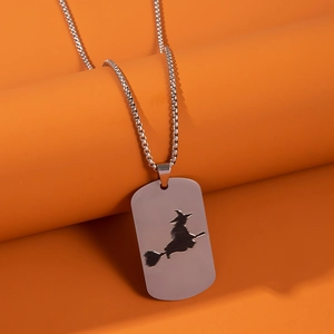 Macro shot of silver stainless steel pendant with witch silhouette on orange background