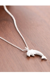 Macro view of 925 sterling silver dolphin pendant showing the S925 hallmark on wood