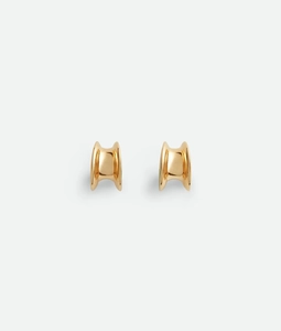 Macro shot of polished 18K gold-plated C-shaped chunky earrings with smooth metal surface