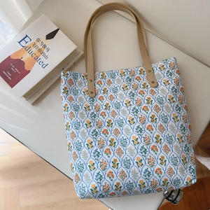 Detail of floral cotton tote bag with reinforced faux leather handles and metal rivets