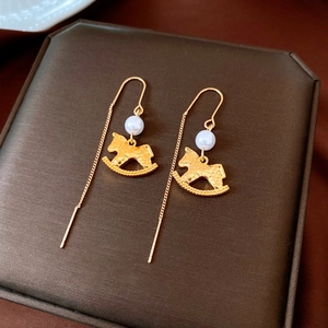 Detail of gold rocking horse earrings with pearls and hammered metal texture