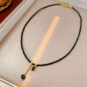Close-up of black beaded necklace with crystal pendant in a beige jewelry box