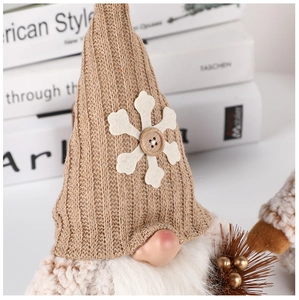 Close-up of a brown knitted Christmas gnome with a snowflake button and long white beard