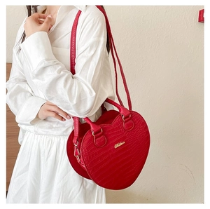 Détail du sac à main cœur rouge en relief crocodile avec logo doré et bandoulière