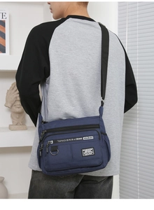 Macro detail of waterproof blue nylon crossbody bag featuring multi-pocket zipper layers