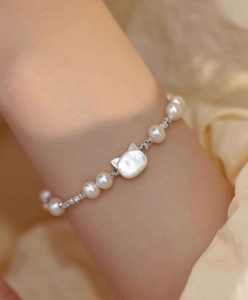 Detail of s925 silver cat charm bracelet with freshwater pearls and white shell