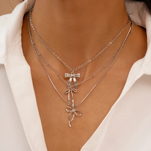 Détail d'un collier multicouche argenté avec trois pendentifs nœuds sur modèle