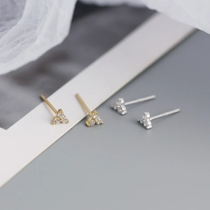 Close-up of gold and silver S925 sterling silver clover stud earrings with sparkling zircons