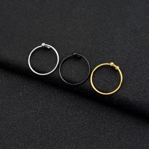 Detail view of silver, black and gold steel nose rings with small ball closures
