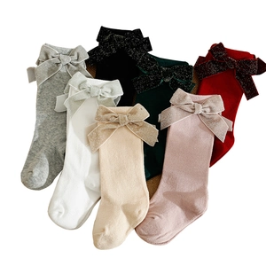 Knee-high baby socks with large glitter bows in multiple colors on a white background