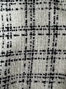 Close-up of high-quality black and white tweed fabric with detailed woven texture