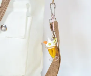 Detalle de un llavero de helado de naranja con crema y pajita colgado en un bolso
