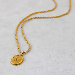 Minimalist gold sunflower pendant necklace with twisted rope chain on grey background