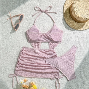 Detailansicht eines rosa dreiteiligen Bikinis mit Blasenstruktur und Strandzubehör