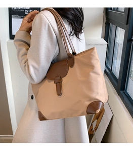 Detailed close-up of nylon and leather patchwork on large khaki tote bag during use
